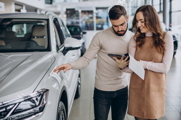 Saleswoman talking customer car showroom