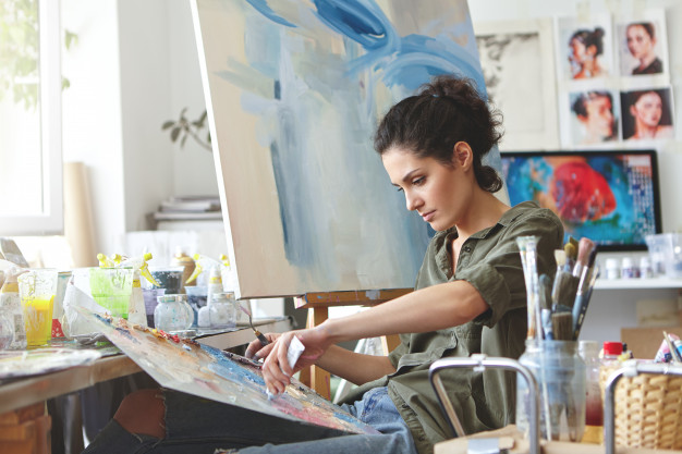 young female student having classes art studio learning how draw landscapes trying mix different watercolors cardboard concentrated woman with dark hair dressed casually painting